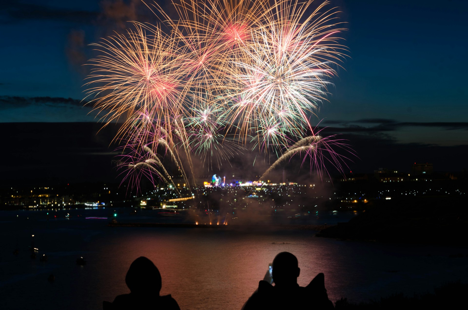 couple sitting on a ridge and watching new year's fireworks